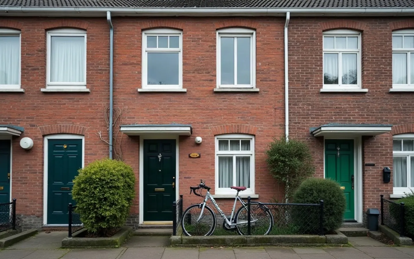 Rij Nederlandse rijtjeswoningen met voordeuren aan de straat, een fiets tegen het hek